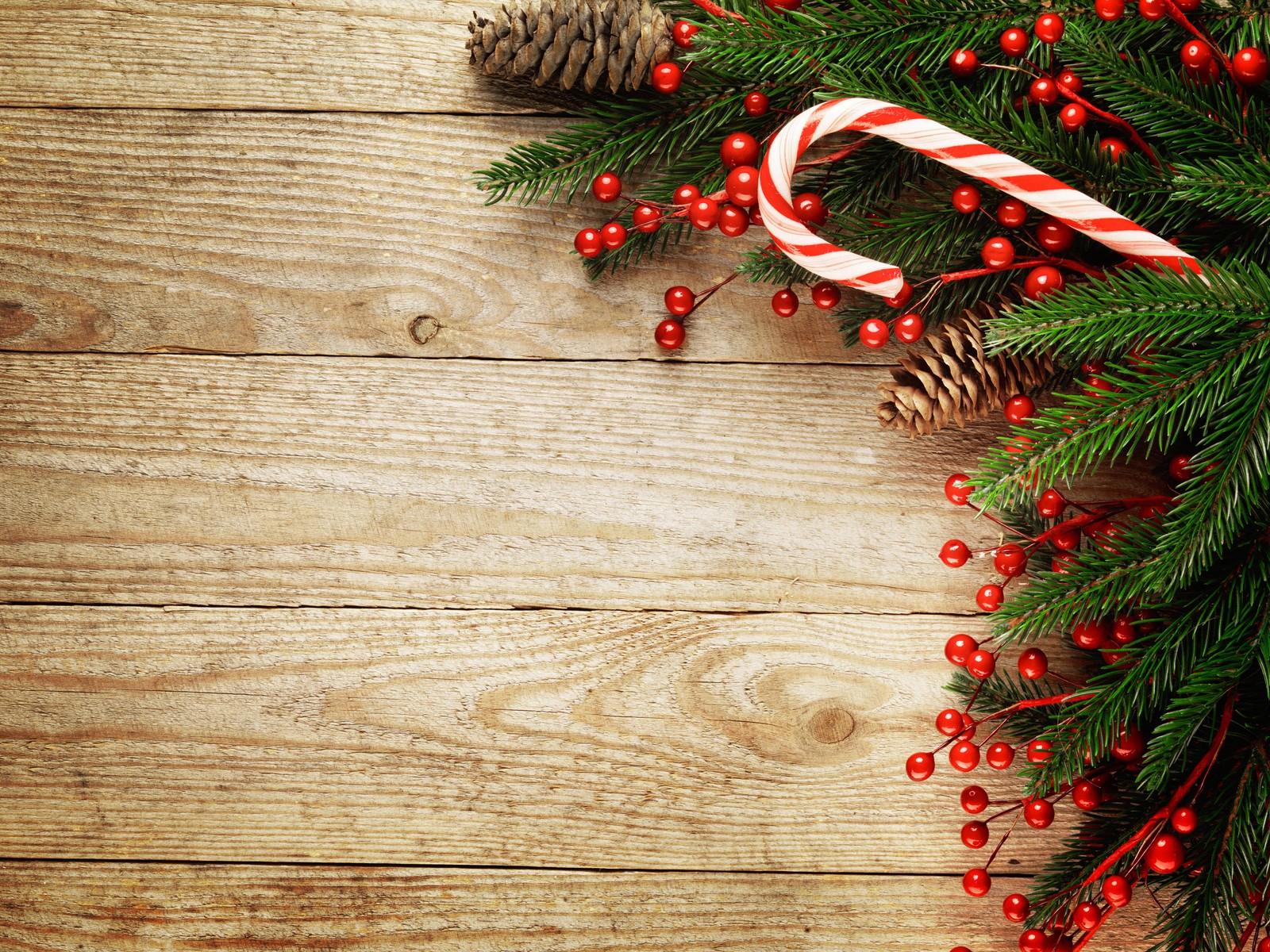 Un fond de noël avec des cannes en sucre et des cônes de pin sur une table en bois (noël, décoration de noël, bois, lumières de noël, sapin de noël)