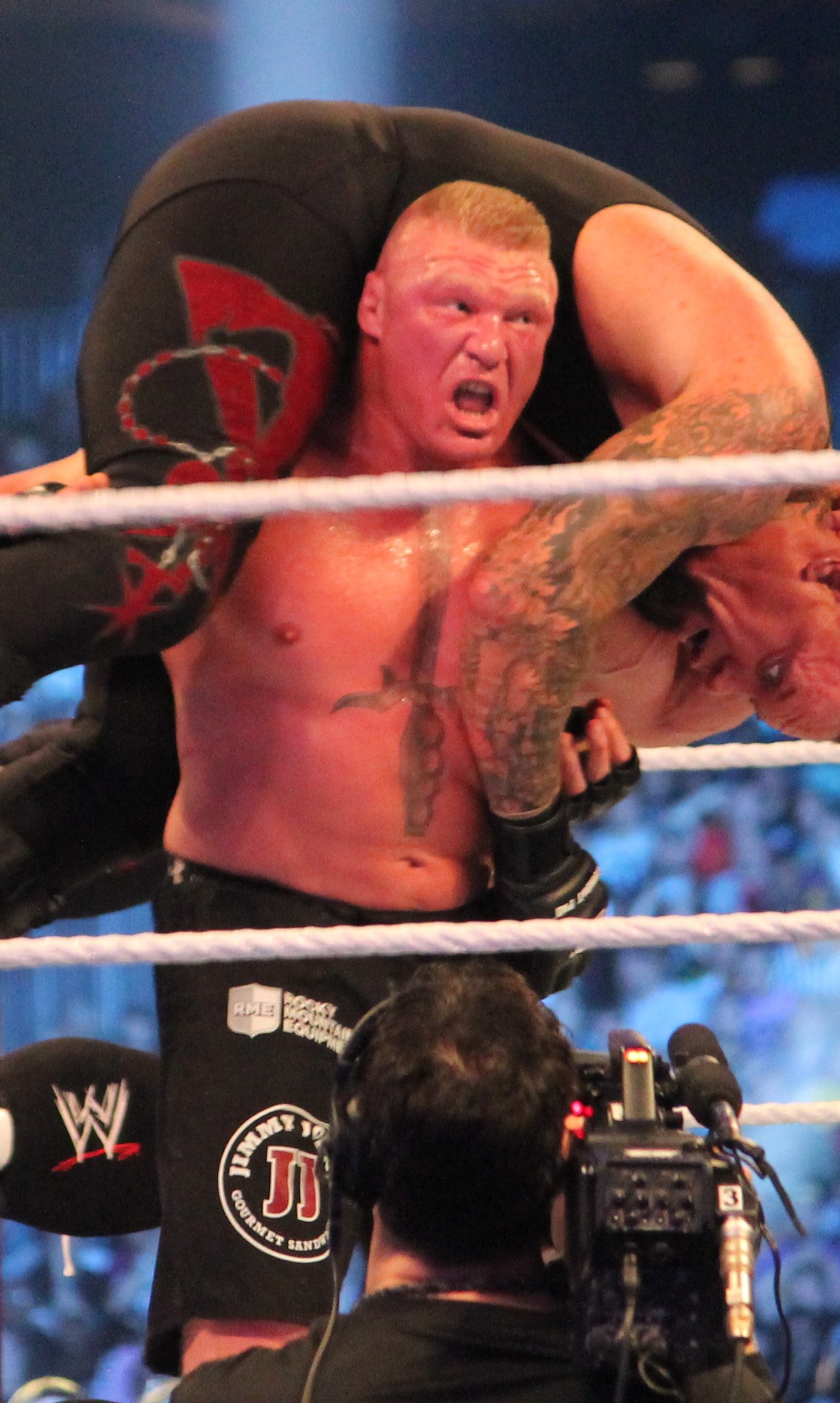 Un luchador con una camiseta negra sostiene a un hombre en un ring de lucha (brock lesnar, wwe)