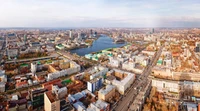 Vue aérienne d'un paysage urbain vibrant présentant un mélange de zones résidentielles, de bâtiments commerciaux et d'espaces verts dans une ville animée.