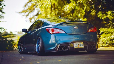 Eleganter blauer Hyundai Genesis Coupe mit sportlichen Felgen in einer malerischen Außenumgebung