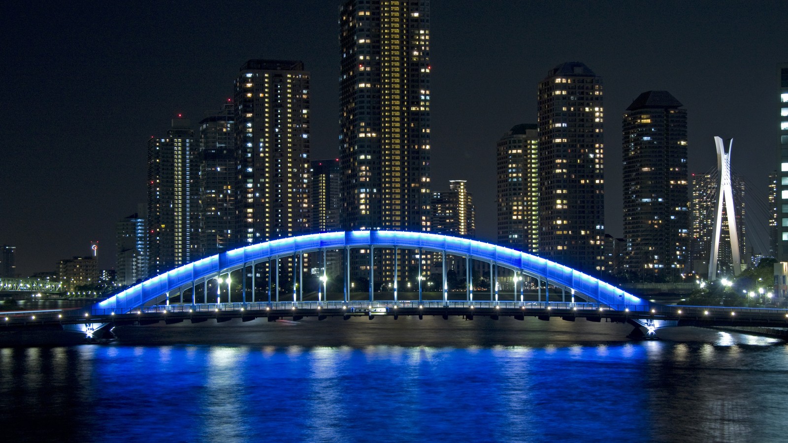 Ponte aérea sobre um rio com uma cidade ao fundo (rio sumida, ponte, noite, azul, bloco de torre)