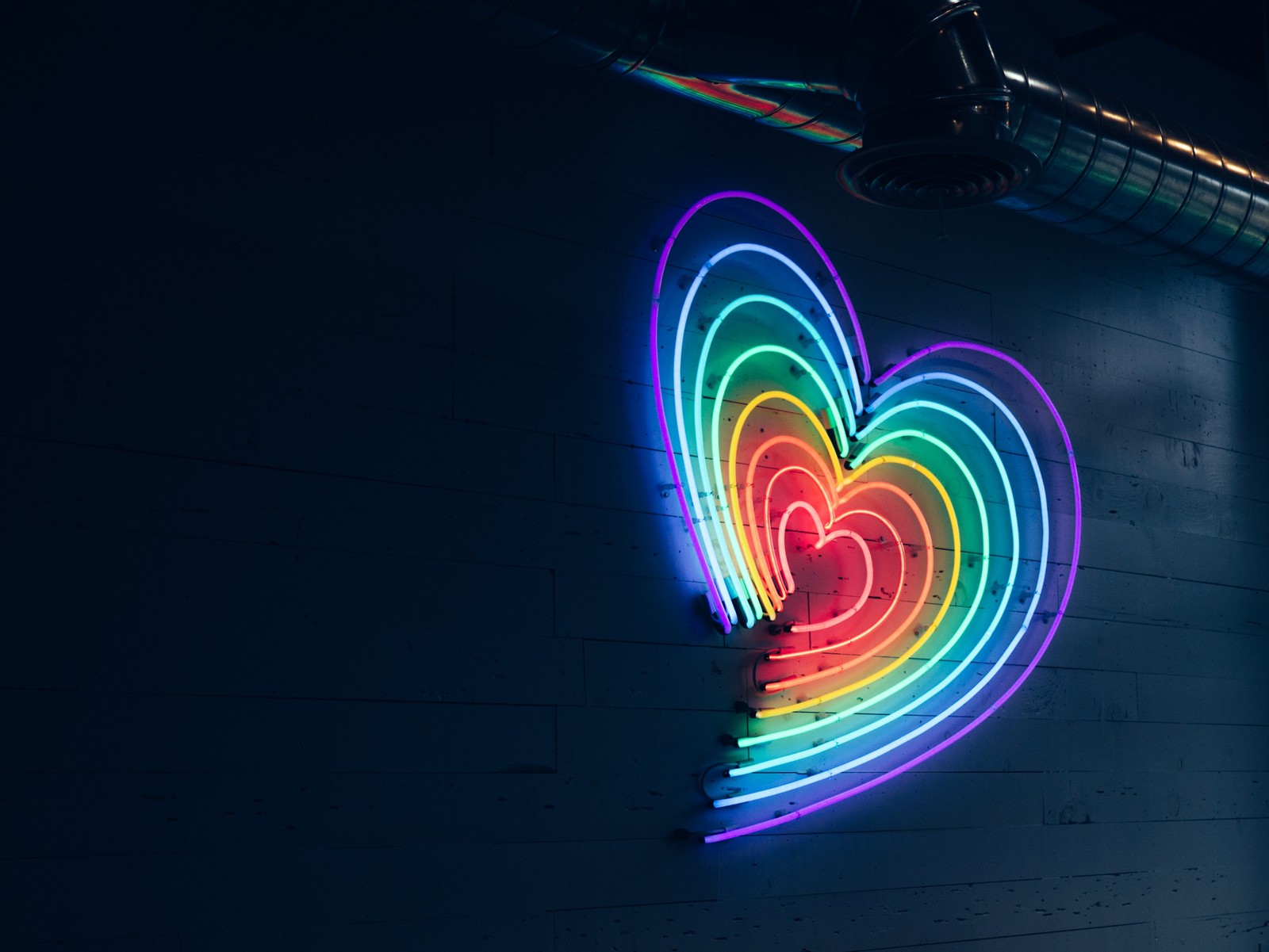 Brightly lit neon heart on a wall in a dark room (neon sign, light, neon, neon lighting, graphics)