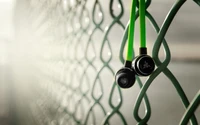 Close-Up of Headphones Hanging on a Green Fence