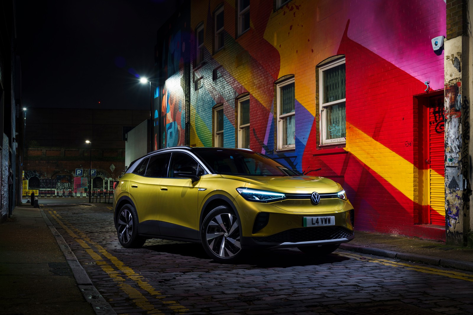 Suv volkswagen amarillo estacionado frente a un edificio colorido (volkswagen id4, primera edición, suv eléctrico, 2021, 5k)