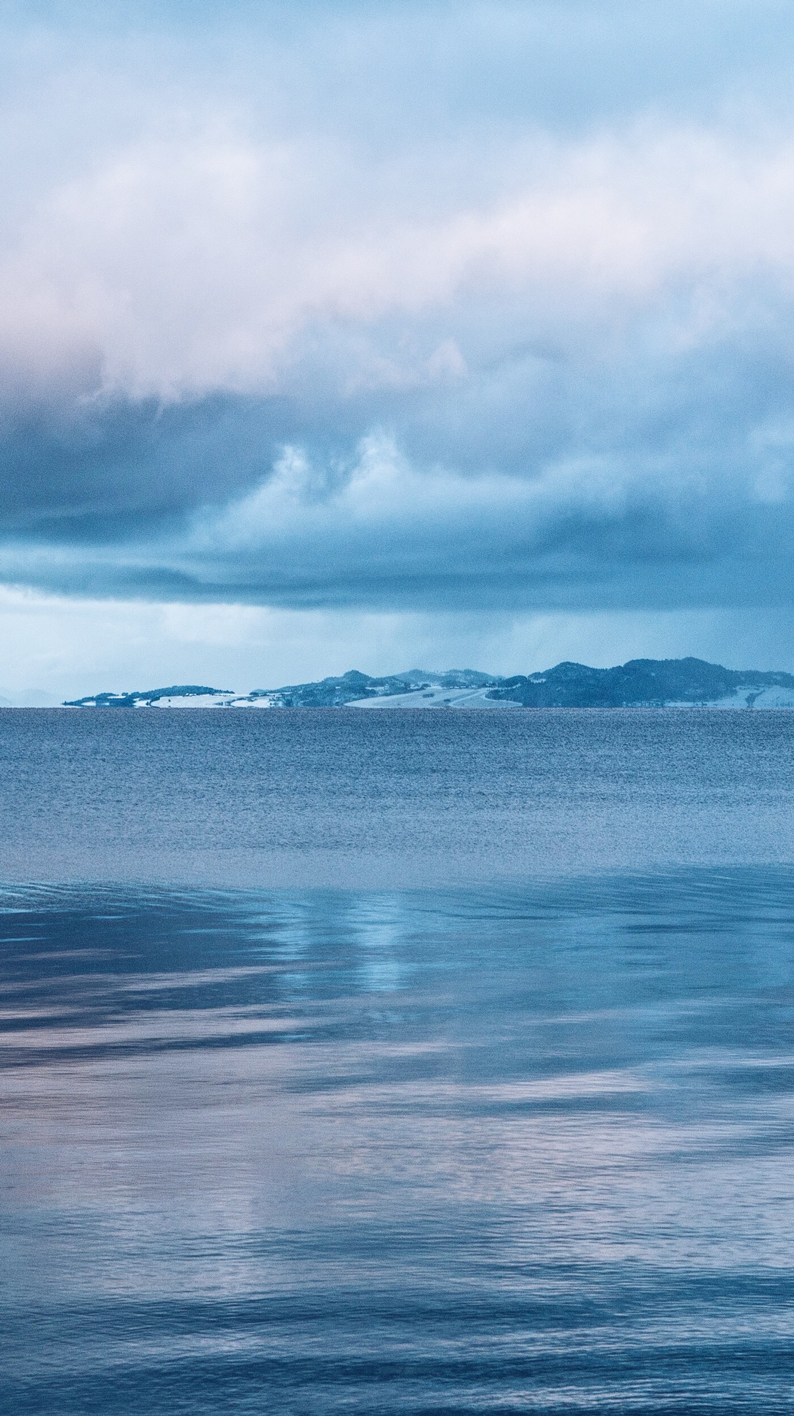 Il y a un bateau solitaire flottant sur l'eau sous un ciel nuageux (beauté, bleu, nuages, fjord, norvège)