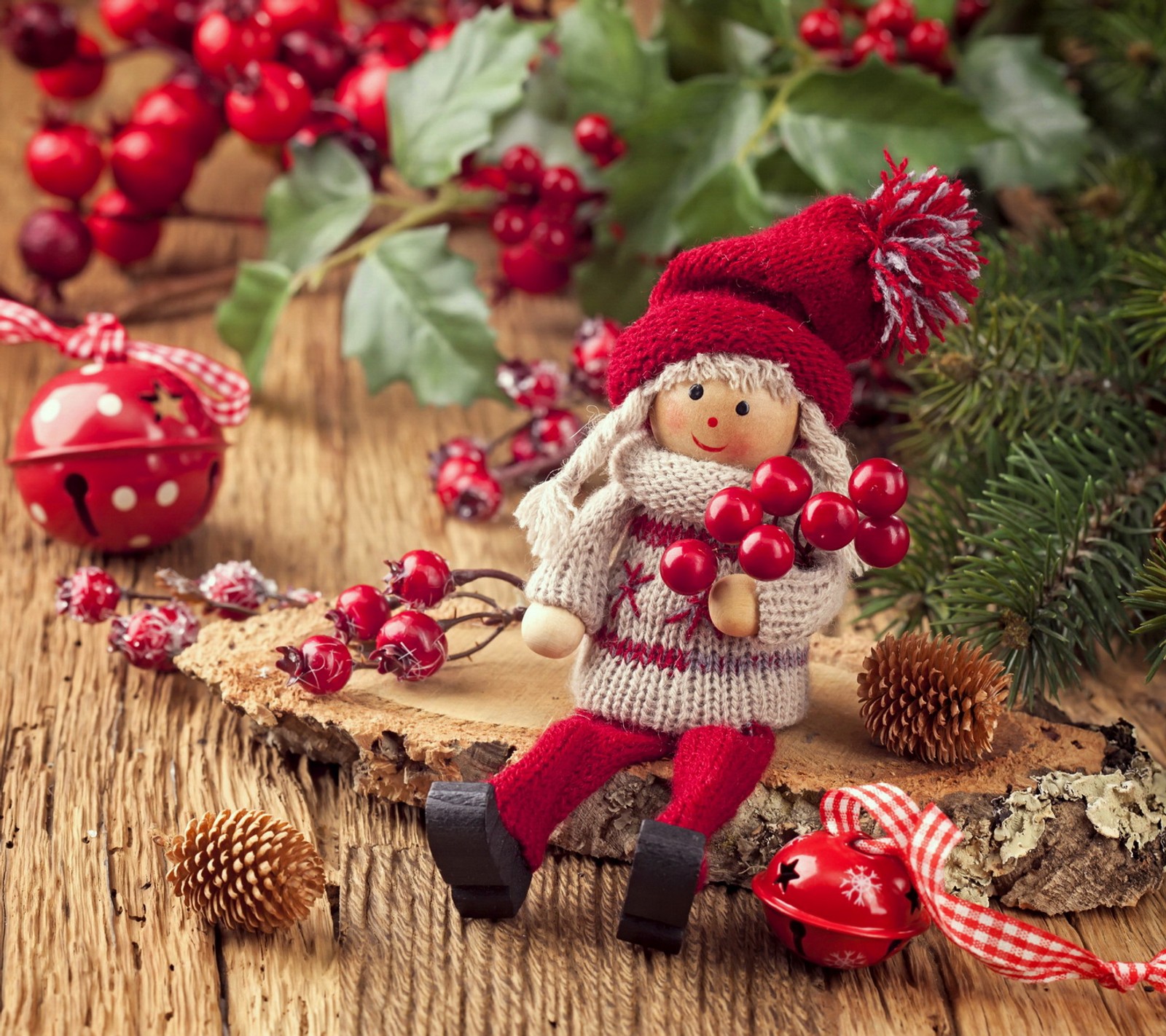 There is a small doll sitting on a piece of wood with decorations (christmas, cute, decoration, merry, toy)