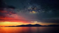 Atardecer vibrante sobre aguas tranquilas bajo un cielo estrellado