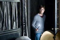 Daniel Radcliffe als Harry Potter mit einem Zauberstab in einem schwach beleuchteten Raum