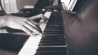 Close-up of hands playing a black and white electric piano