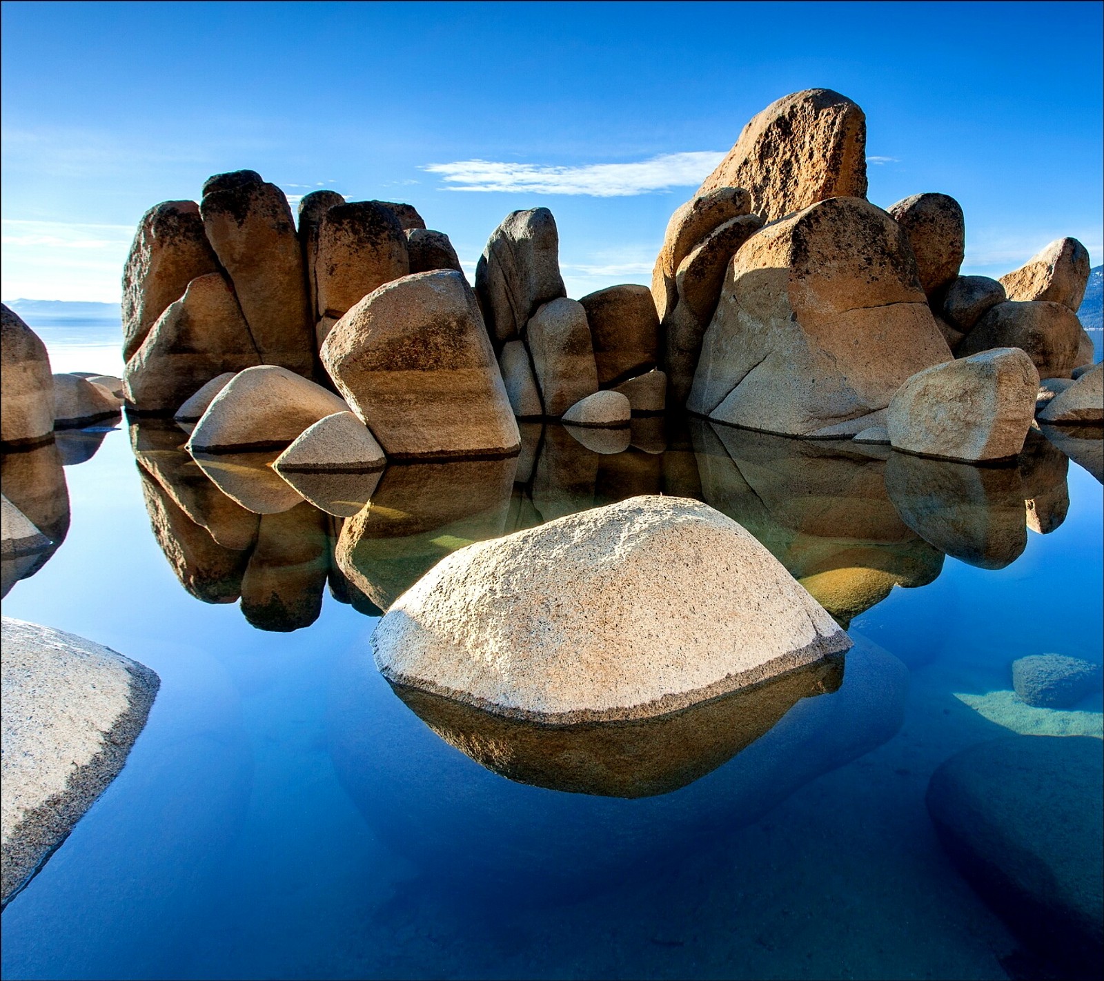 Hay una gran formación rocosa en el agua con rocas en el fondo (mar, piedras)