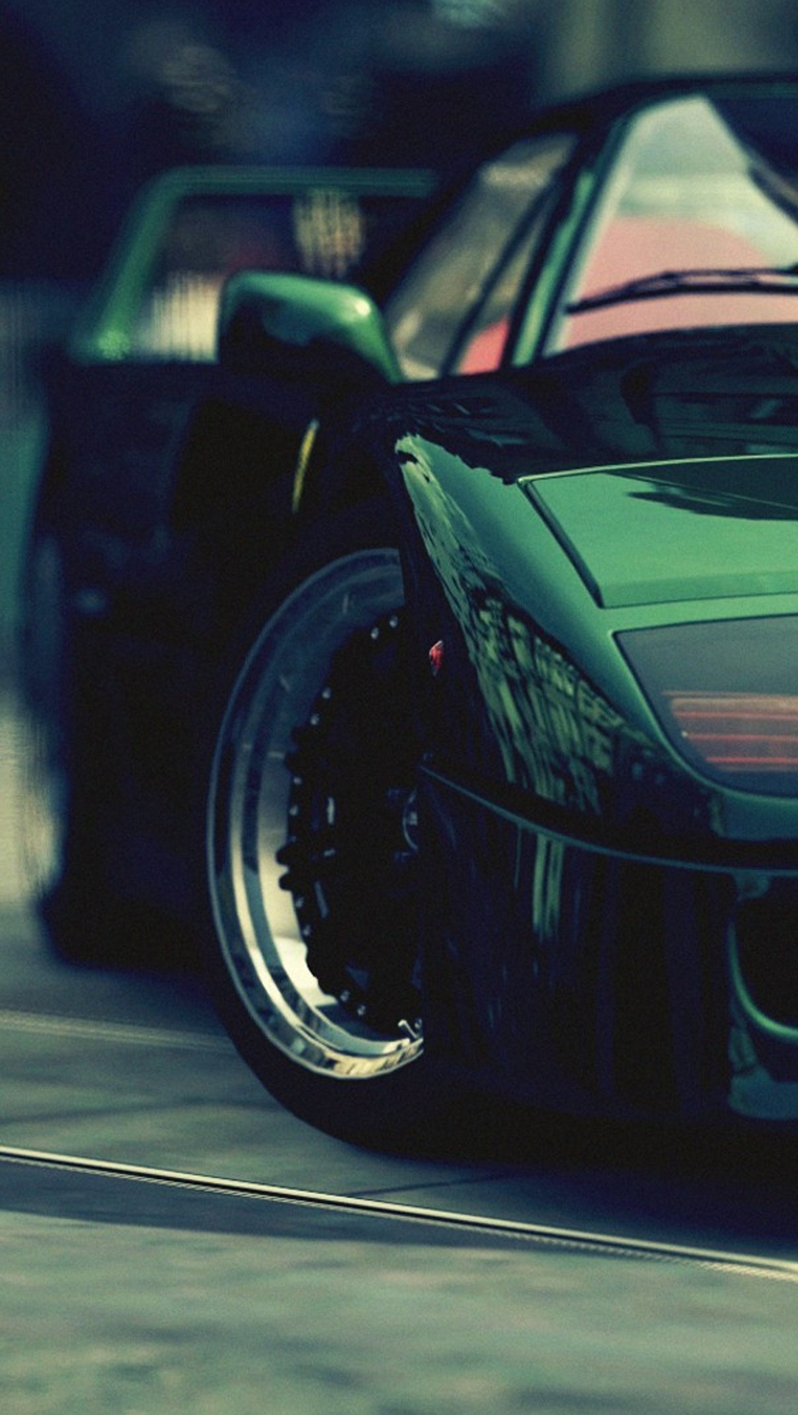 A close up of a black sports car driving down a street (car, green, tuned)