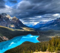 Impresionante paisaje montañoso con lago turquesa y nubes dramáticas