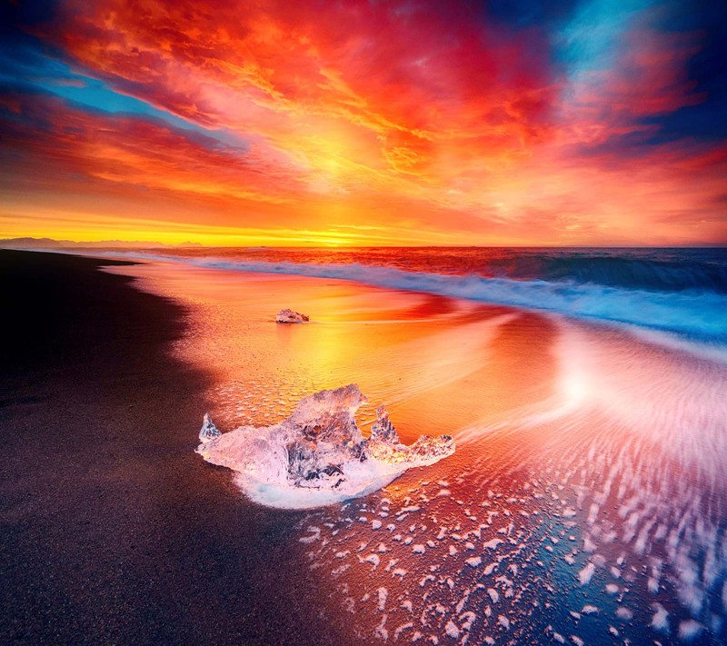 Un grand iceberg sur la plage avec un coucher de soleil coloré en arrière-plan (beau, paysage)