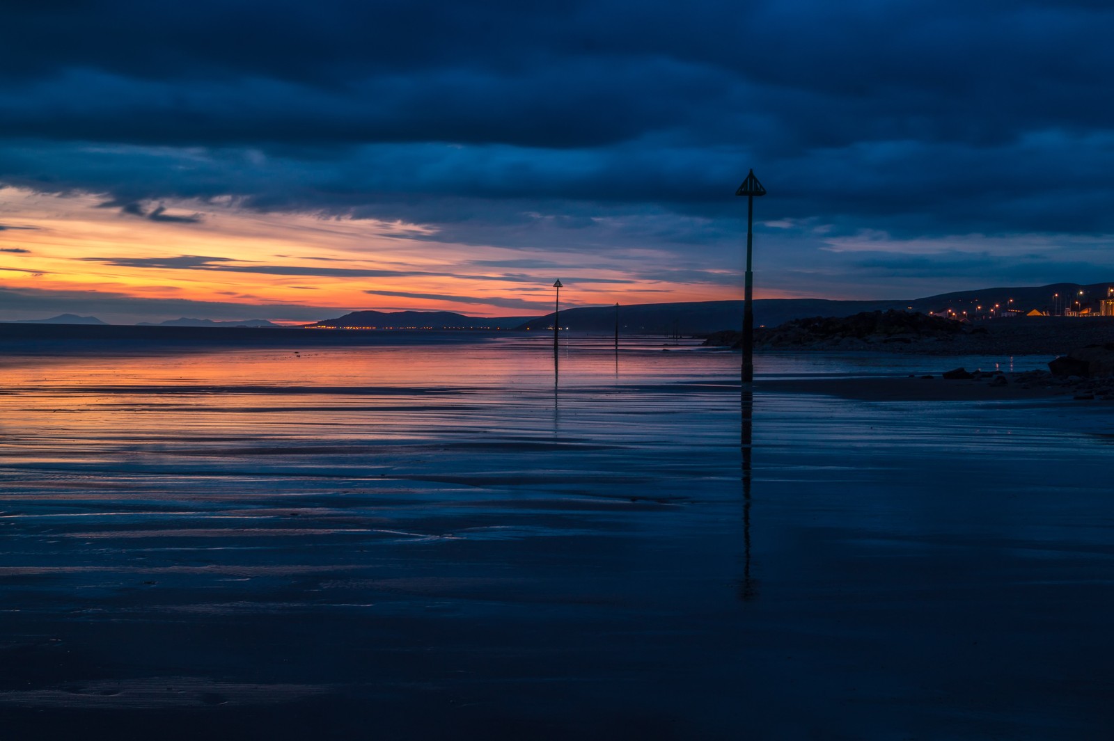 Une vue d'une plage avec un lampadaire et un plan d'eau (horizon, coucher de soleil, mer, bleu, eau)