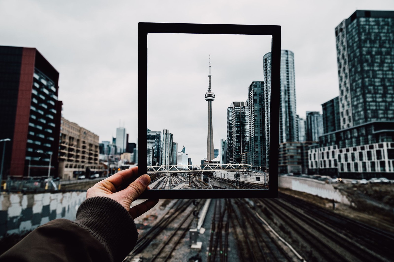 Quelqu'un tenant une image d'une ville dans un cadre (tour cn, cn tower, tour, zone urbaine, ville)