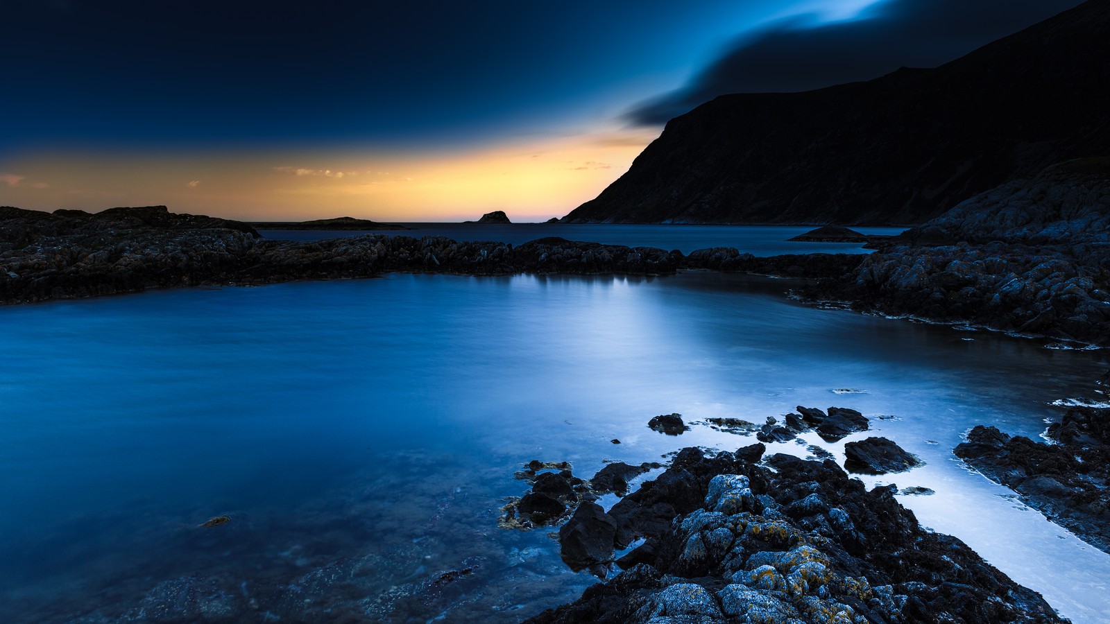 Uma foto de longa exposição de um pôr do sol sobre o oceano com pedras e água (por do sol, mar, corpo de água, natureza, azul)