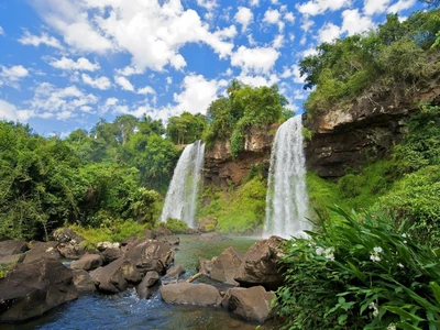 Cataratas do Iguaçu: Uma majestosa cachoeira cercada por vegetação exuberante e céus azuis claros.