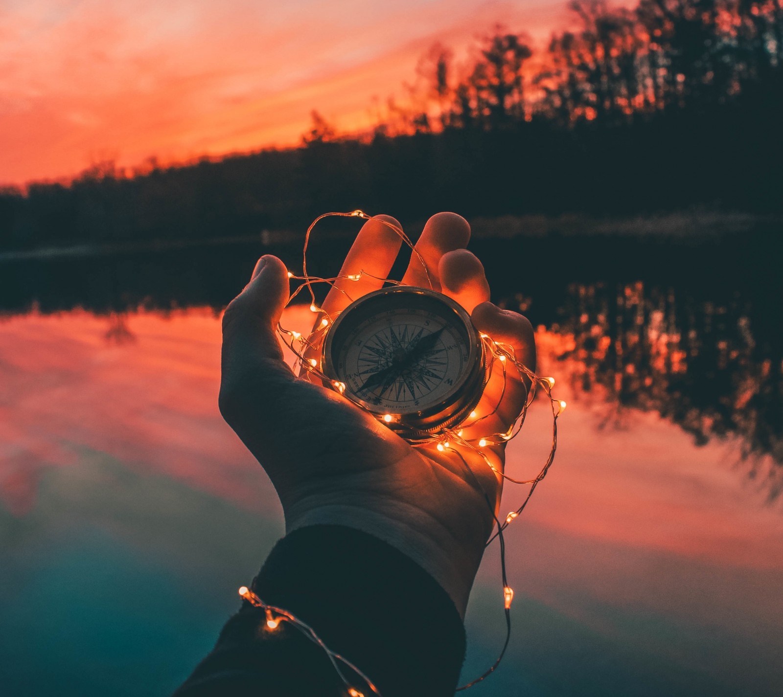 Alguém segurando um relógio com luzes de corda nas mãos (bússola, mãos, luzes)