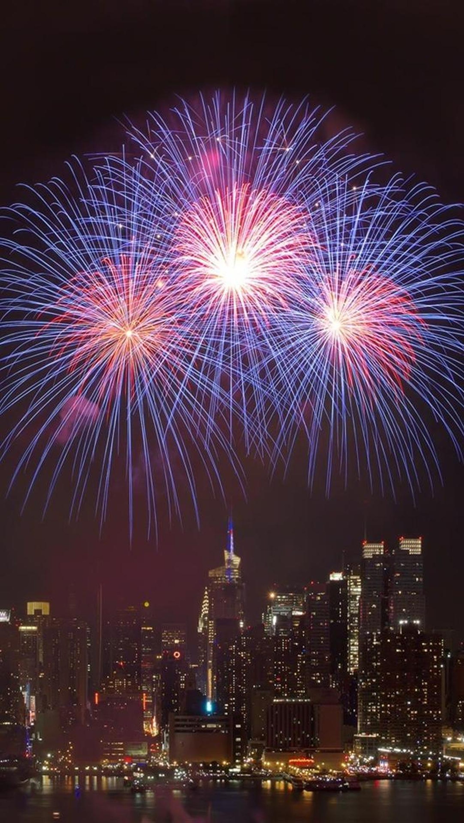 Des feux d'artifice s'illuminent au-dessus de la ligne d'horizon de la ville la nuit (ville, feux dartifice)