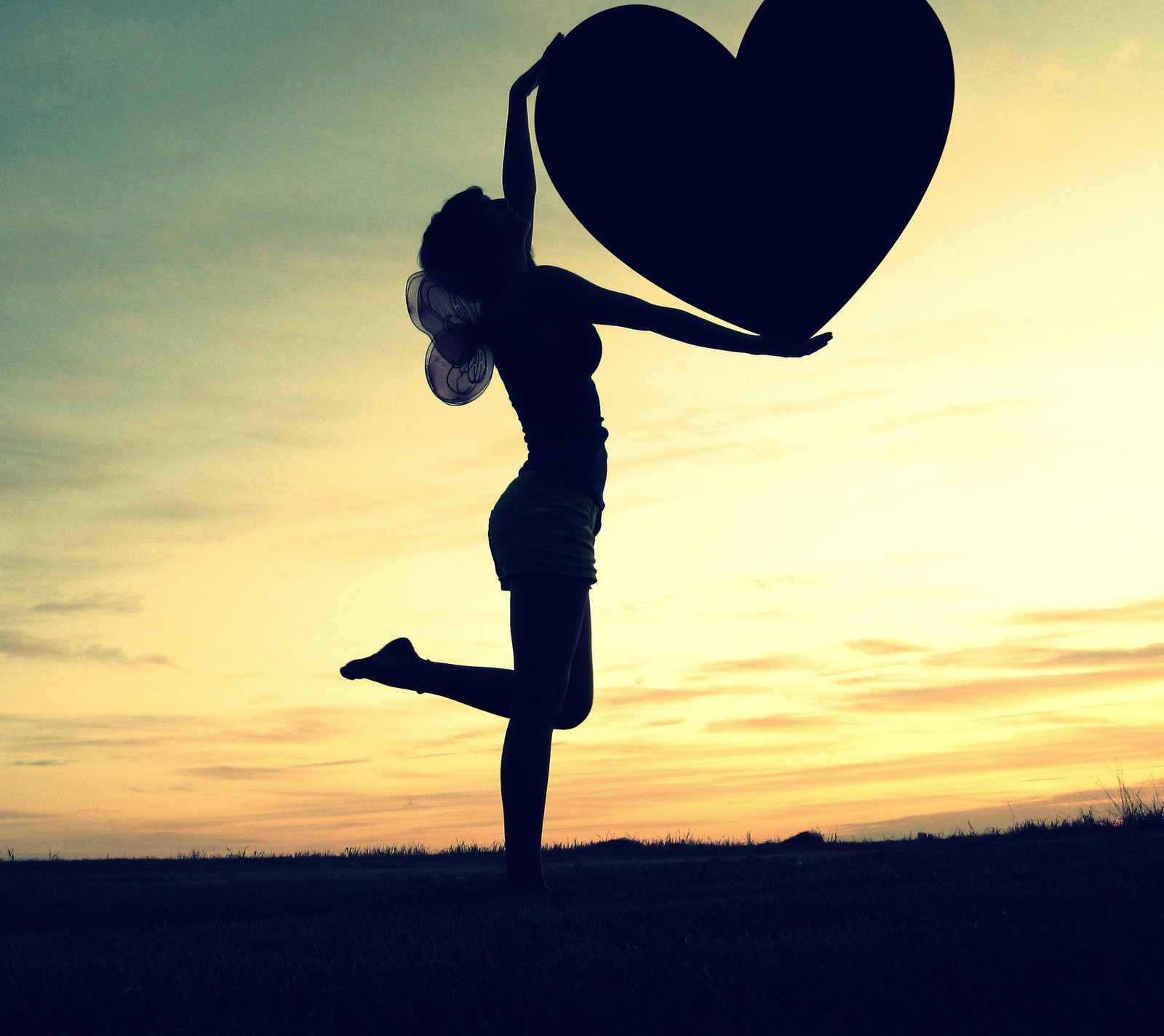 Silhouette d'une femme tenant un objet en forme de cœur dans les airs (cœur, amour)