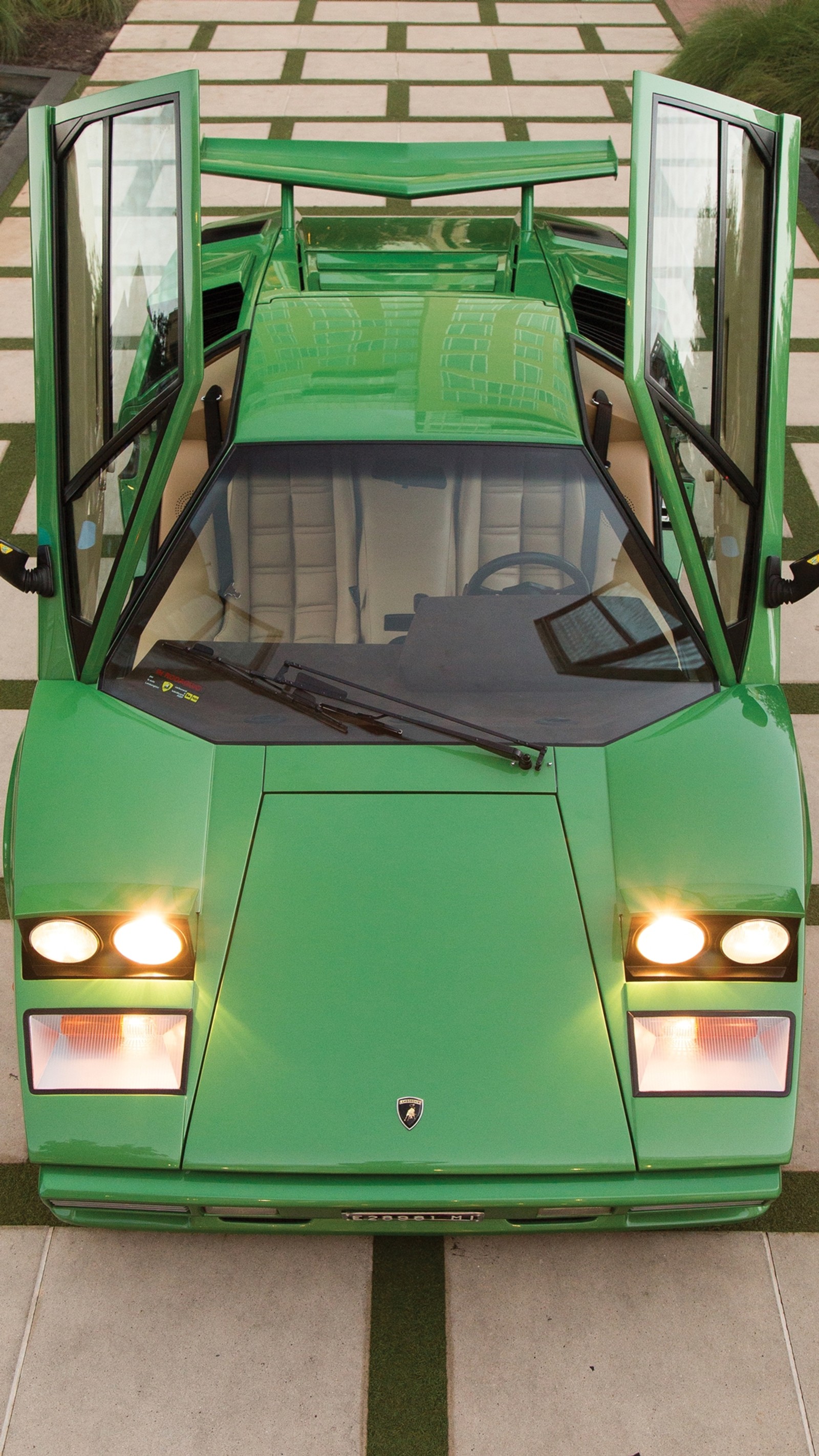 A close up of a green lamborgon parked on a sidewalk (auto, car, classic, countach, lambo)