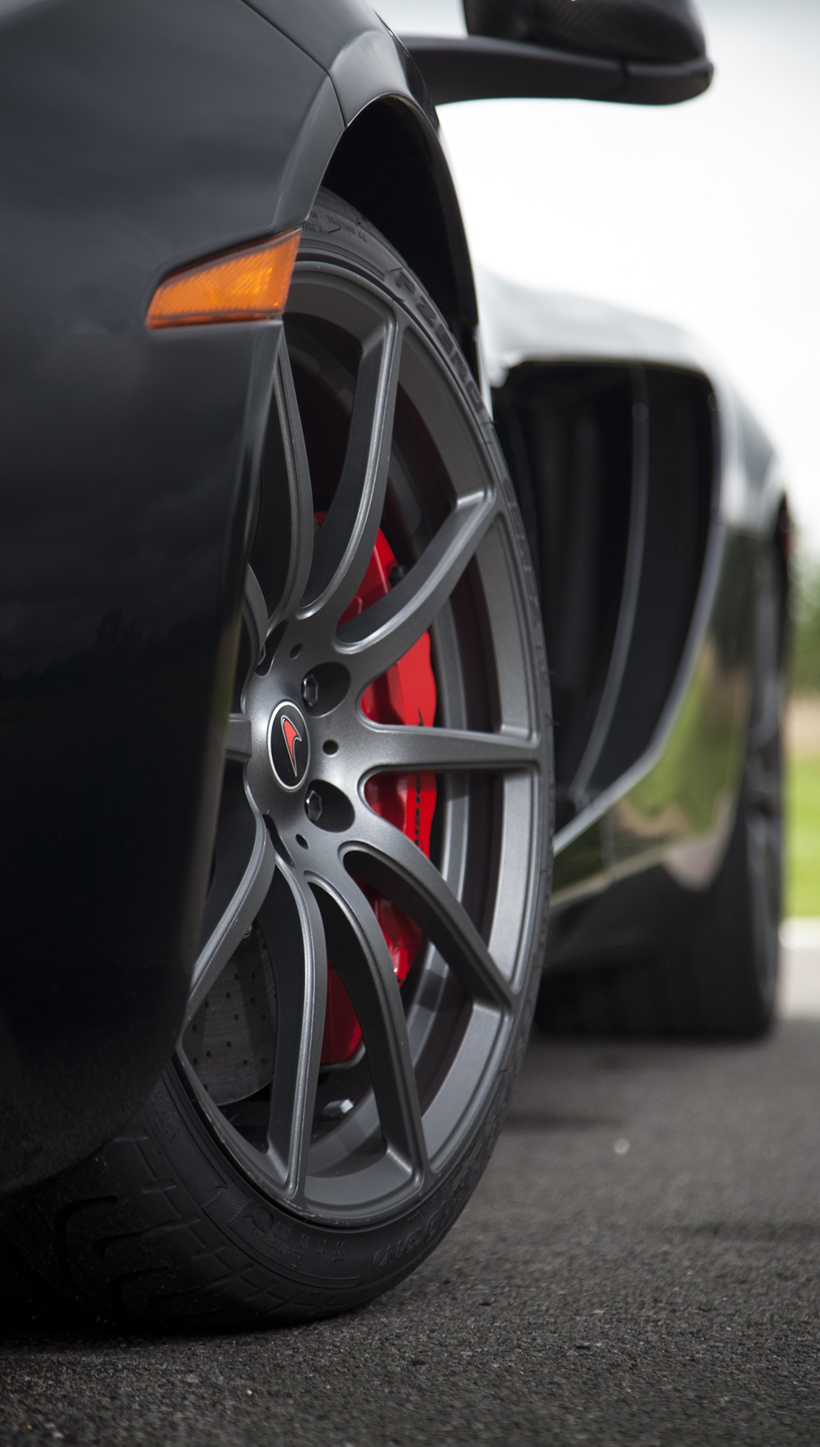 A close up of a black sports car with red brake discs (car, mclaren, mclaren mp4)