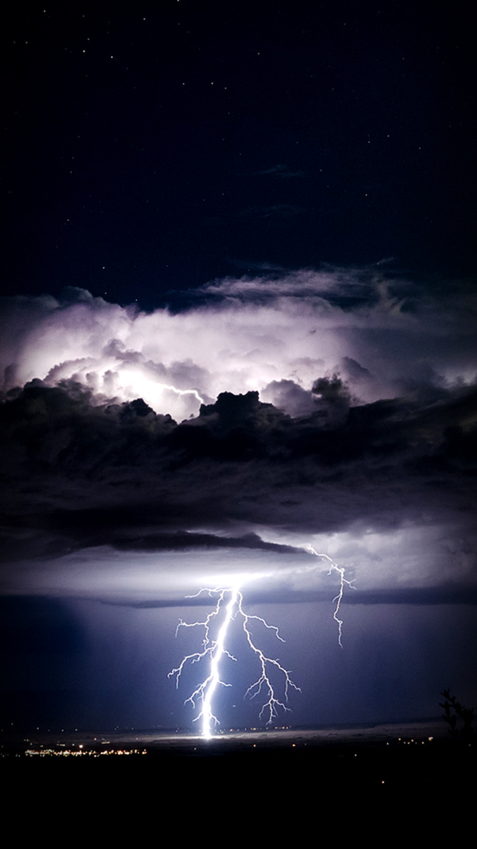 Lightning strikes through the night sky over a city (blue, storm)