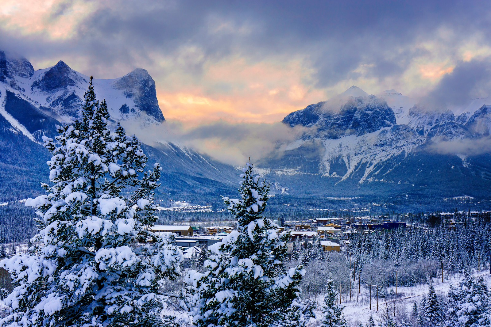 Una vista de una cordillera con una ciudad a lo lejos (banff, invierno, formas montañosas, montaña, naturaleza)