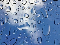 Primer plano de gotas de agua que reflejan un cielo azul