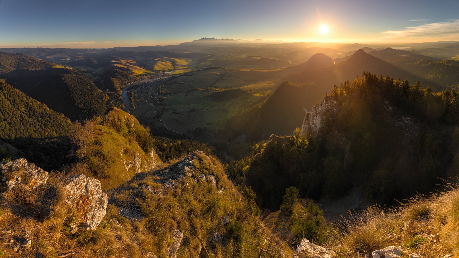 A view of a mountain range with a sun setting over the valley (sunset, mountain, mountainous landforms, wilderness, hill)