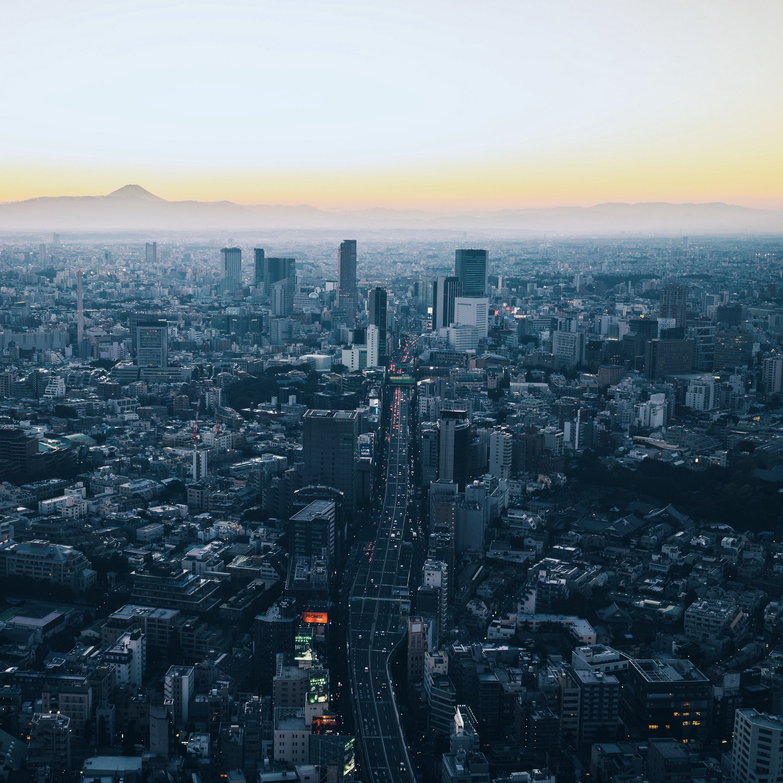 Vista aérea de una ciudad con una carretera y una montaña a lo lejos (paisaje urbano, área urbana, ciudad, metrópolis, rascacielos)