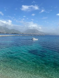 Águas azuis serenas com um barco perto do horizonte montanhoso