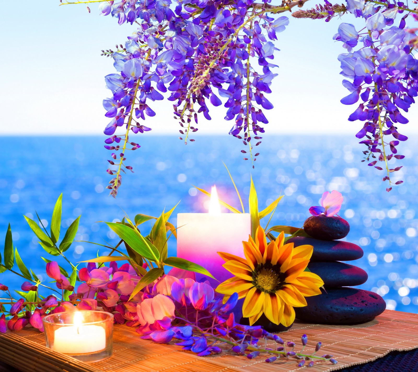 Flores e velas em uma mesa com vista para o oceano (velas, conceito de spa, pedras água do mar)