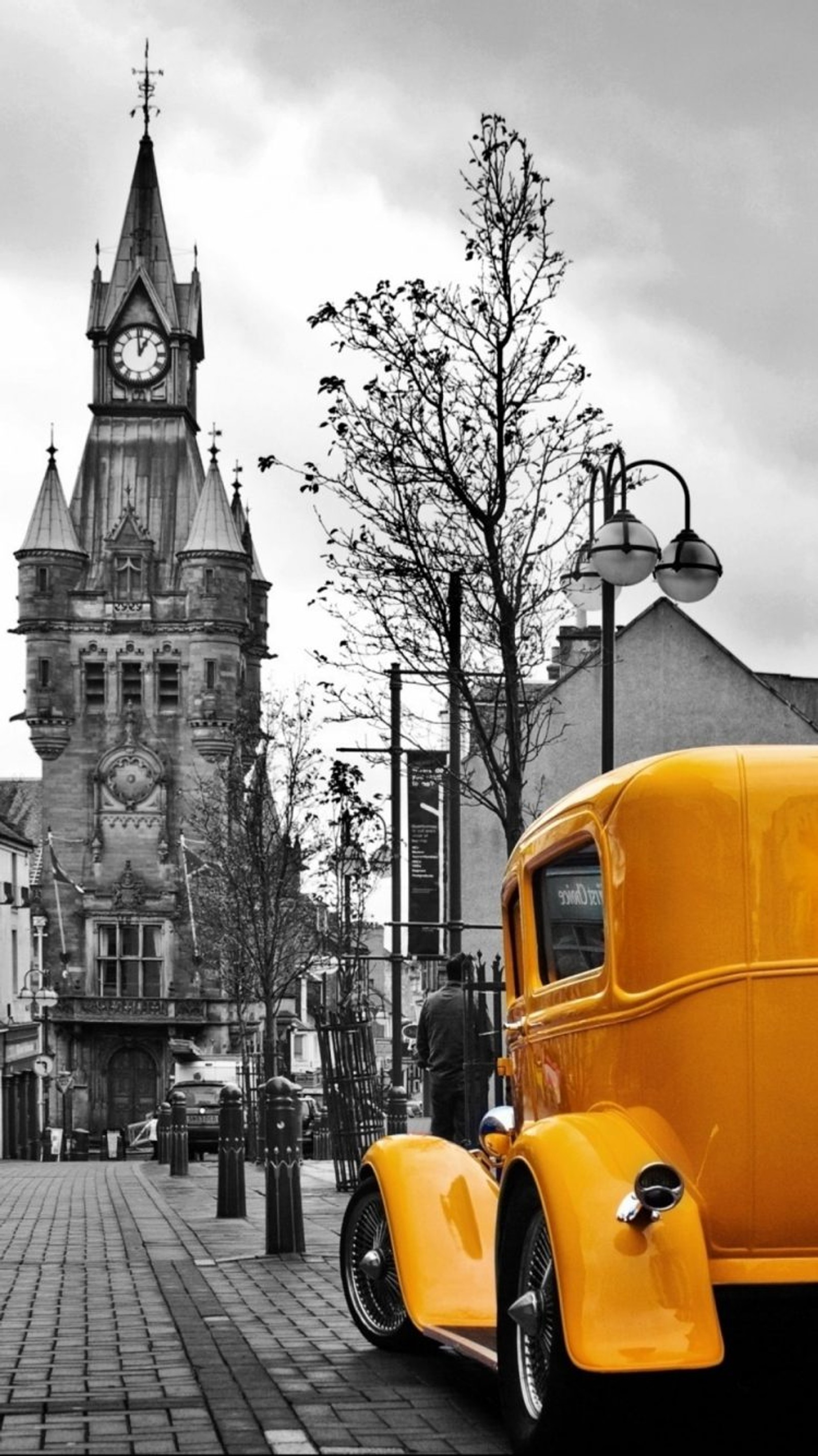 Yellow car parked on brick road in front of large clock tower (church, retro, vintage car)