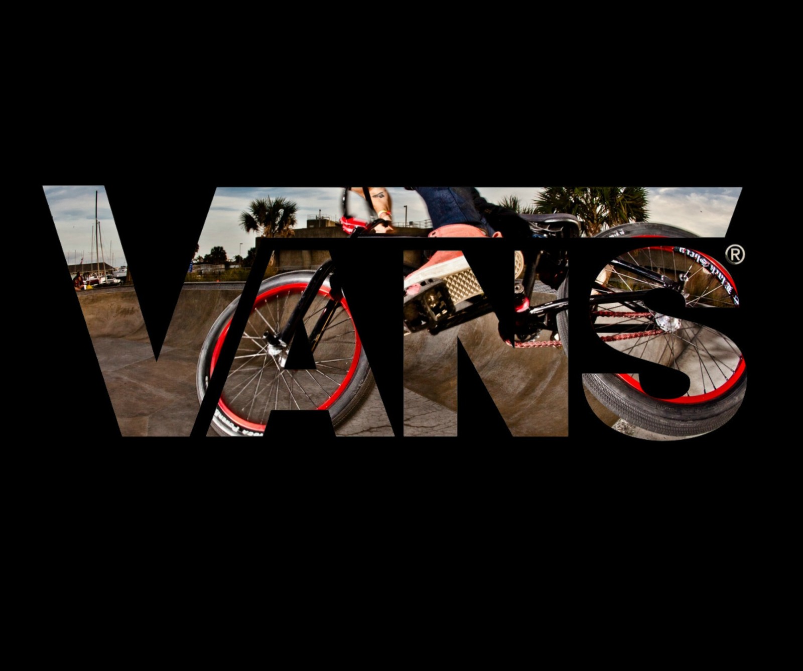 There is a man riding a bike on a ramp with the word v on it (bicycle, bmx, brand, logo, vans)