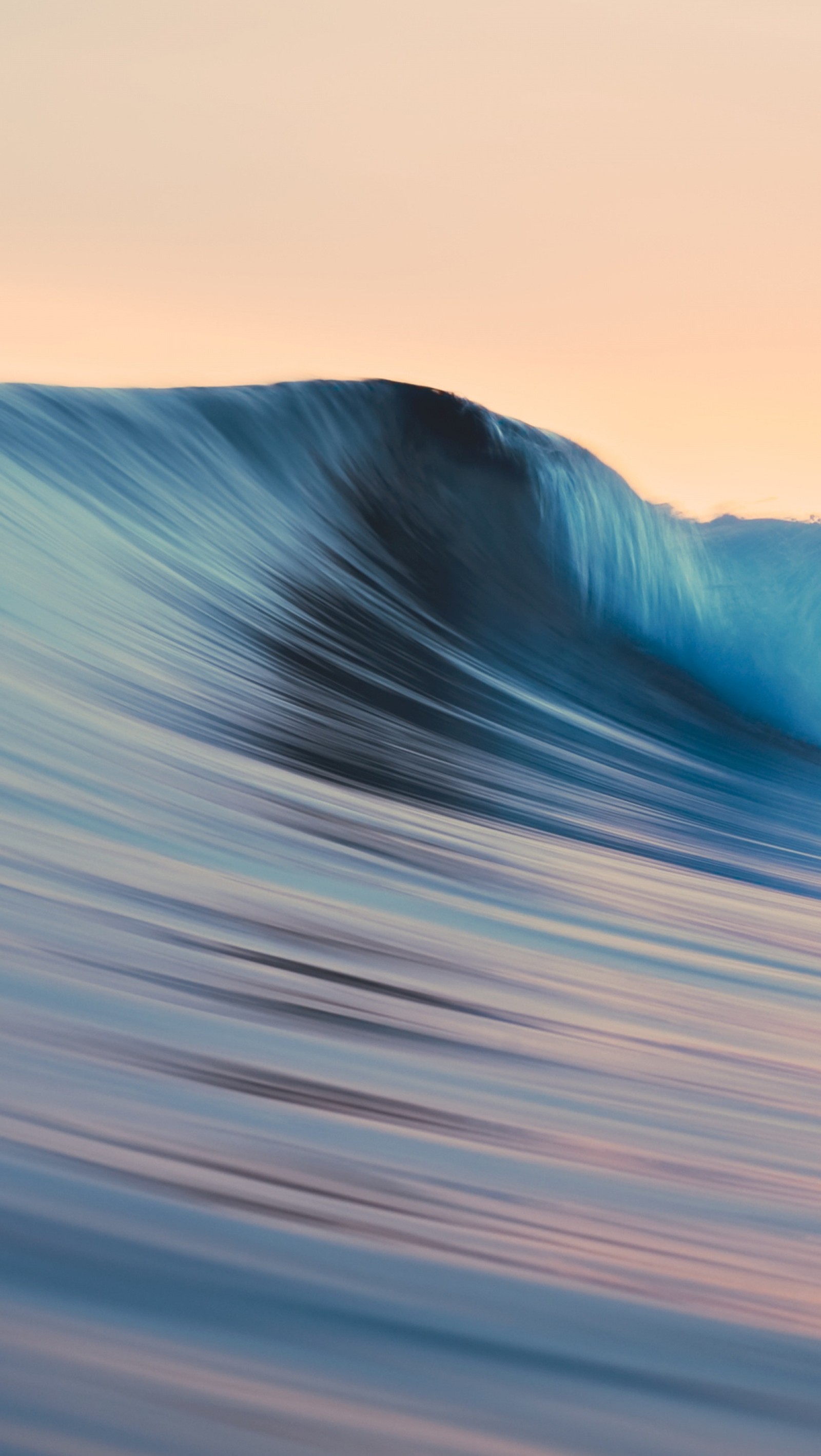 Surfeur chevauchant une vague dans l'océan au coucher du soleil avec un ciel rose (pomme, mac)