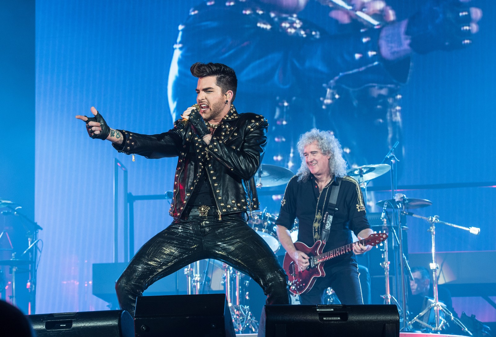 Arafed image of a man in a leather outfit on stage with a guitar (music artist, rock concert, concert, queen, performance)