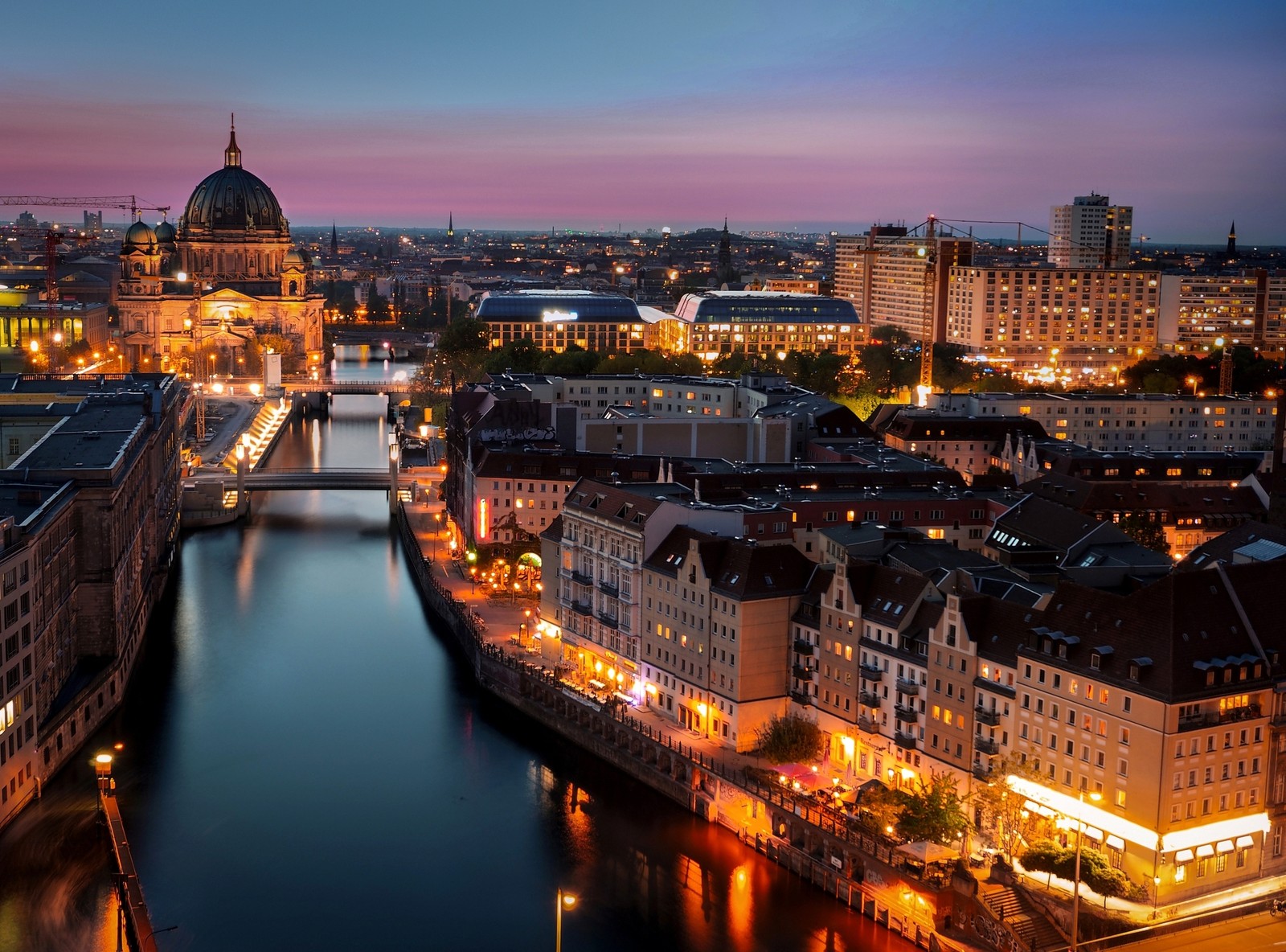 Una vista aérea de una ciudad con un río y un puente de noche (ciudad, iluminación, paisaje urbano, noche, área urbana)