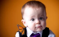 Säugling mit einem Schmetterling auf der Schulter vor orangefarbenem Hintergrund