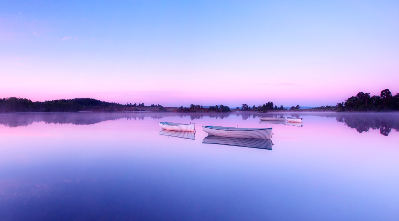 Des bateaux flottant sur un lac avec un ciel rose en arrière-plan (loch rusky, écosse, wee boats, tôt le matin, lac miroir)