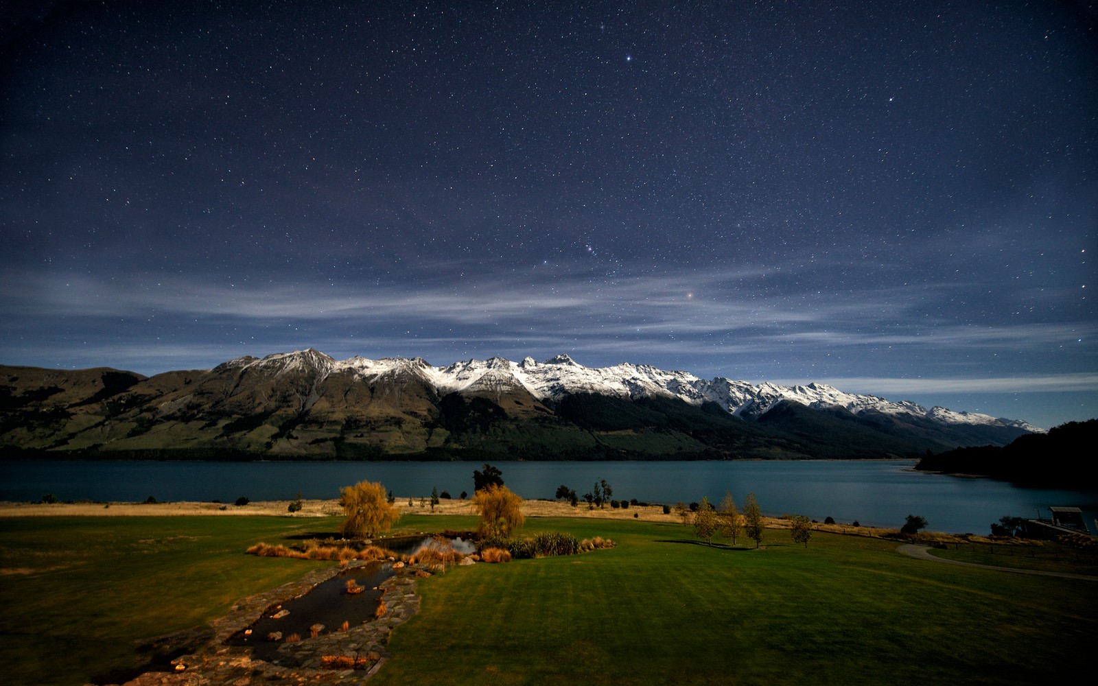 A view of a lake and mountains with a sky full of stars (lake wakatipu, night time, queenstown, new zealand, glacier mountains)