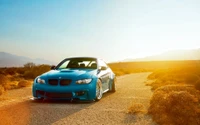 Impresionante BMW azul en una carretera desértica al atardecer