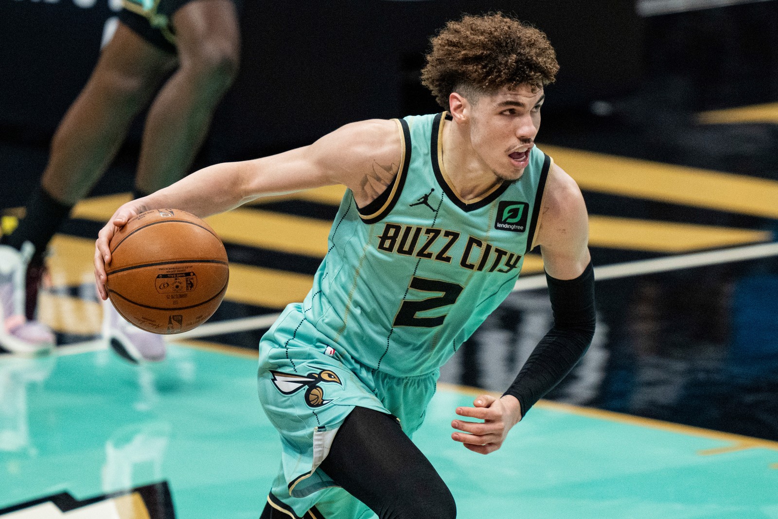 Um close em um jogador de basquete driblando uma bola em uma quadra (lamelo ball, 5k, jogador de basquete, nba, charlotte hornets)