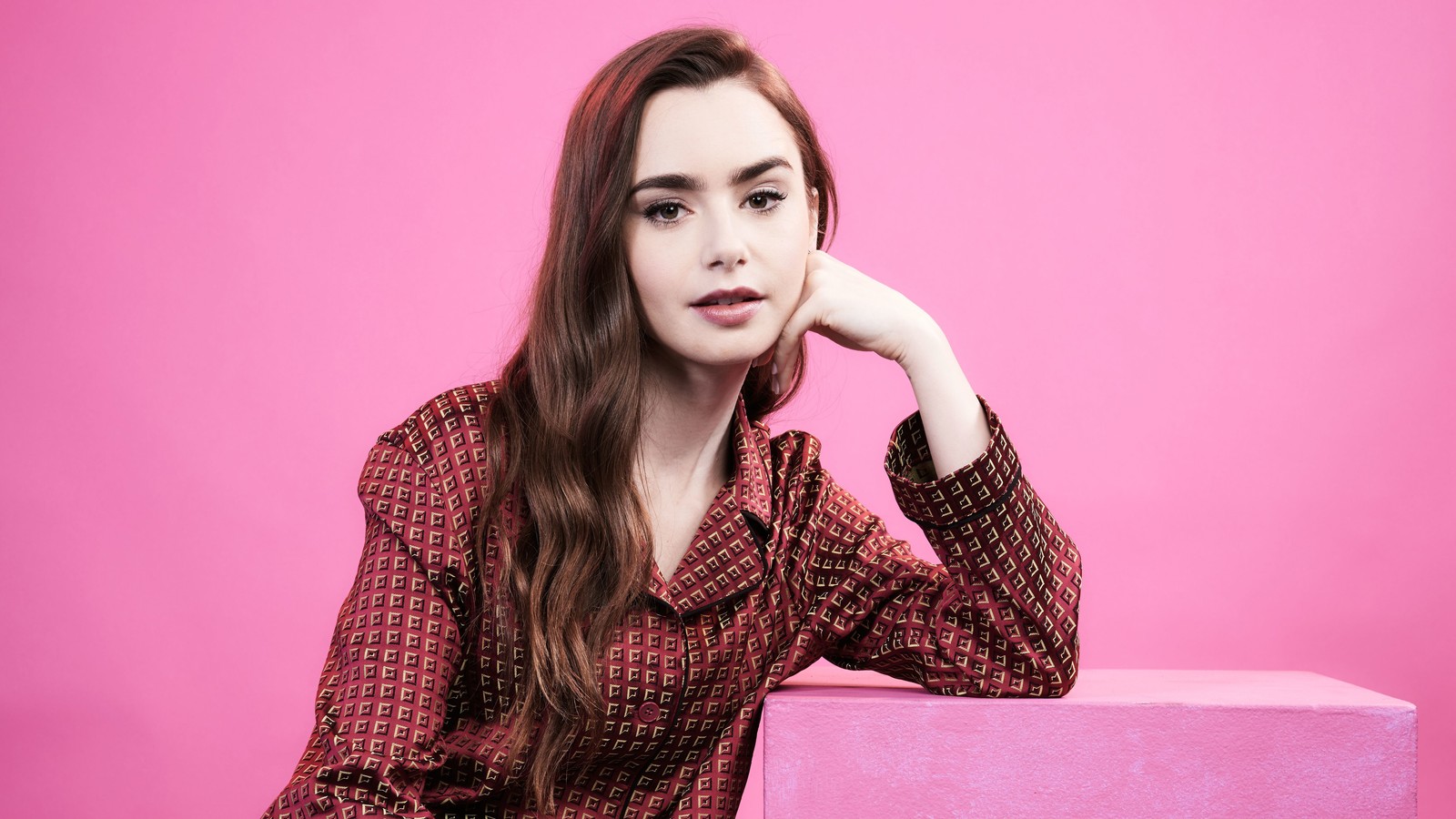 Femme arabe assise sur une boîte rose avec la main sur le menton (lily collins, actrice, célébrité, femmes, filles)