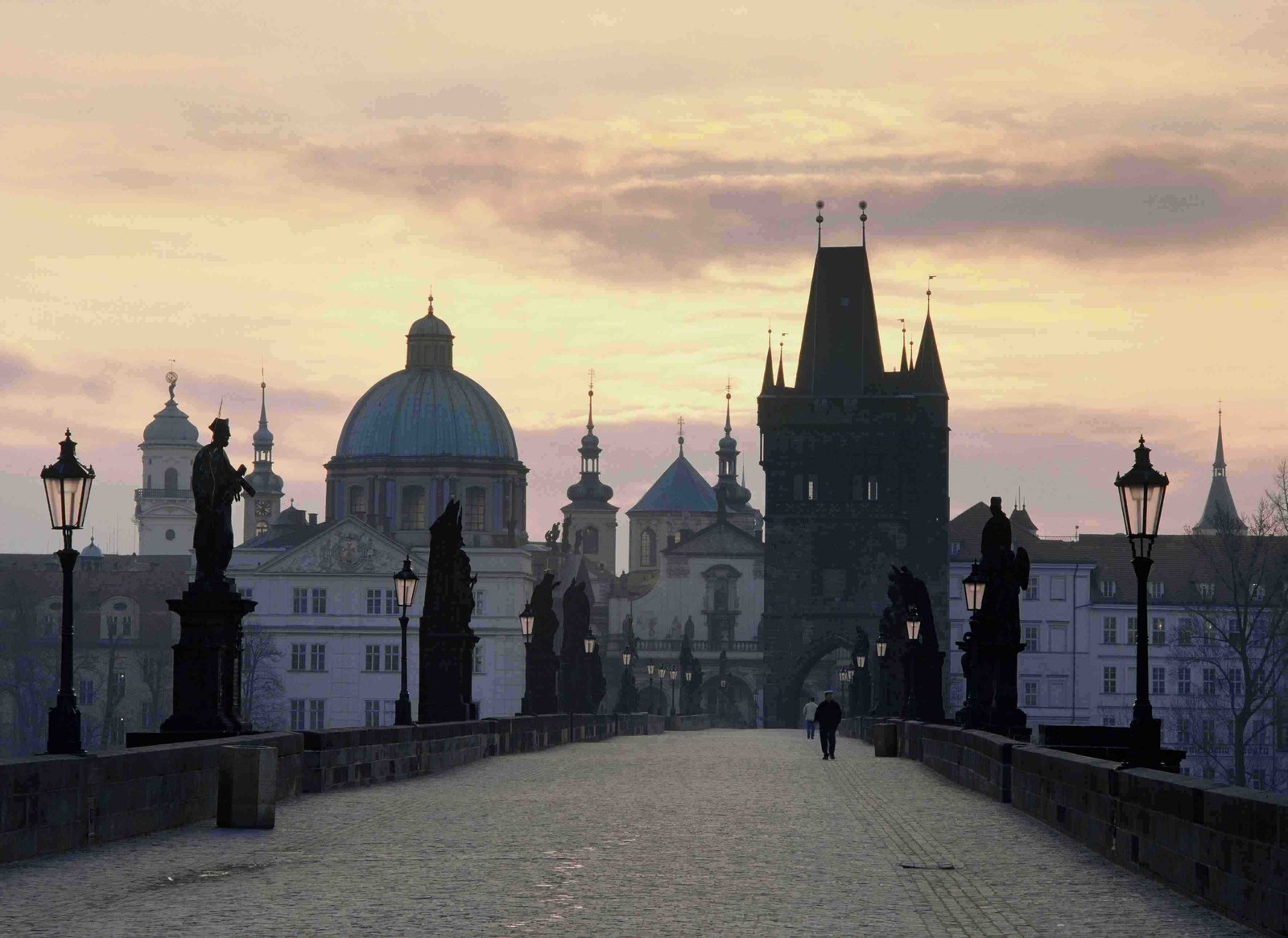 Eine seitliche ansicht einer brücke mit einer person, die darüber geht (sehenswürdigkeit, karlsbrücke, charles bridge, historische stätte, gebäude)