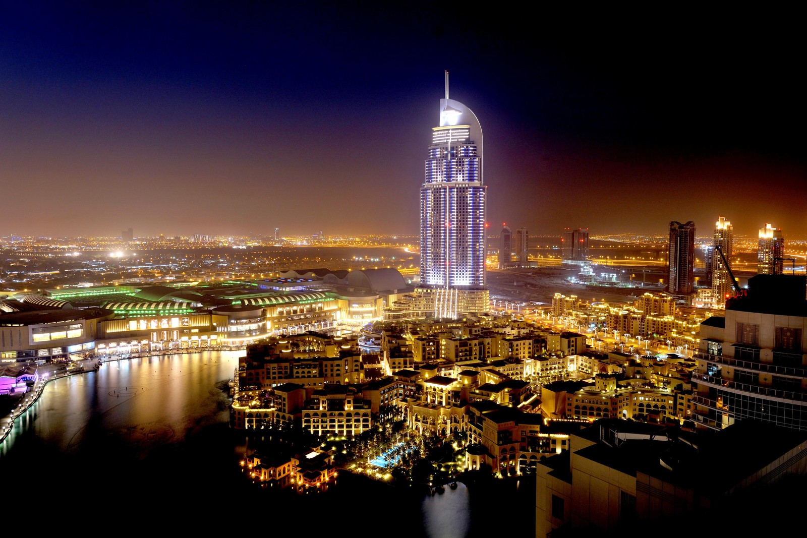 Uma vista de uma cidade à noite com um rio e uma ponte (burj khalifa, dubai mall, the dubai mall, praia de jumeirah, paisagem urbana)