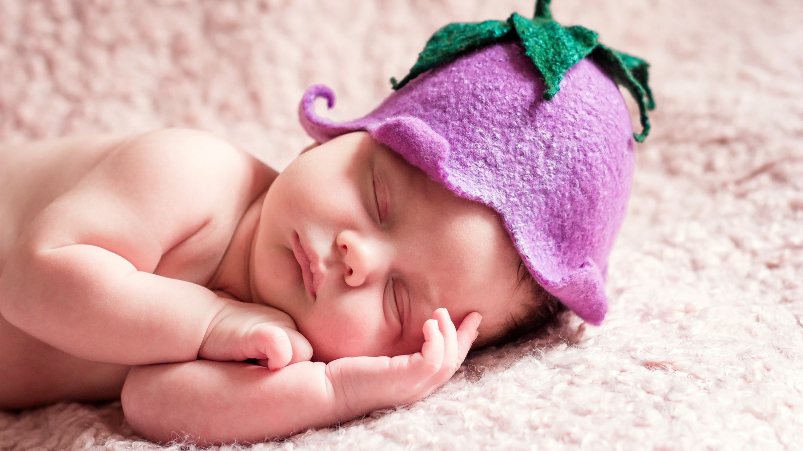 Image floue d'un bébé portant un chapeau violet dormant sur une couverture rose (nourrisson, sommeil, visage, nez, joue)