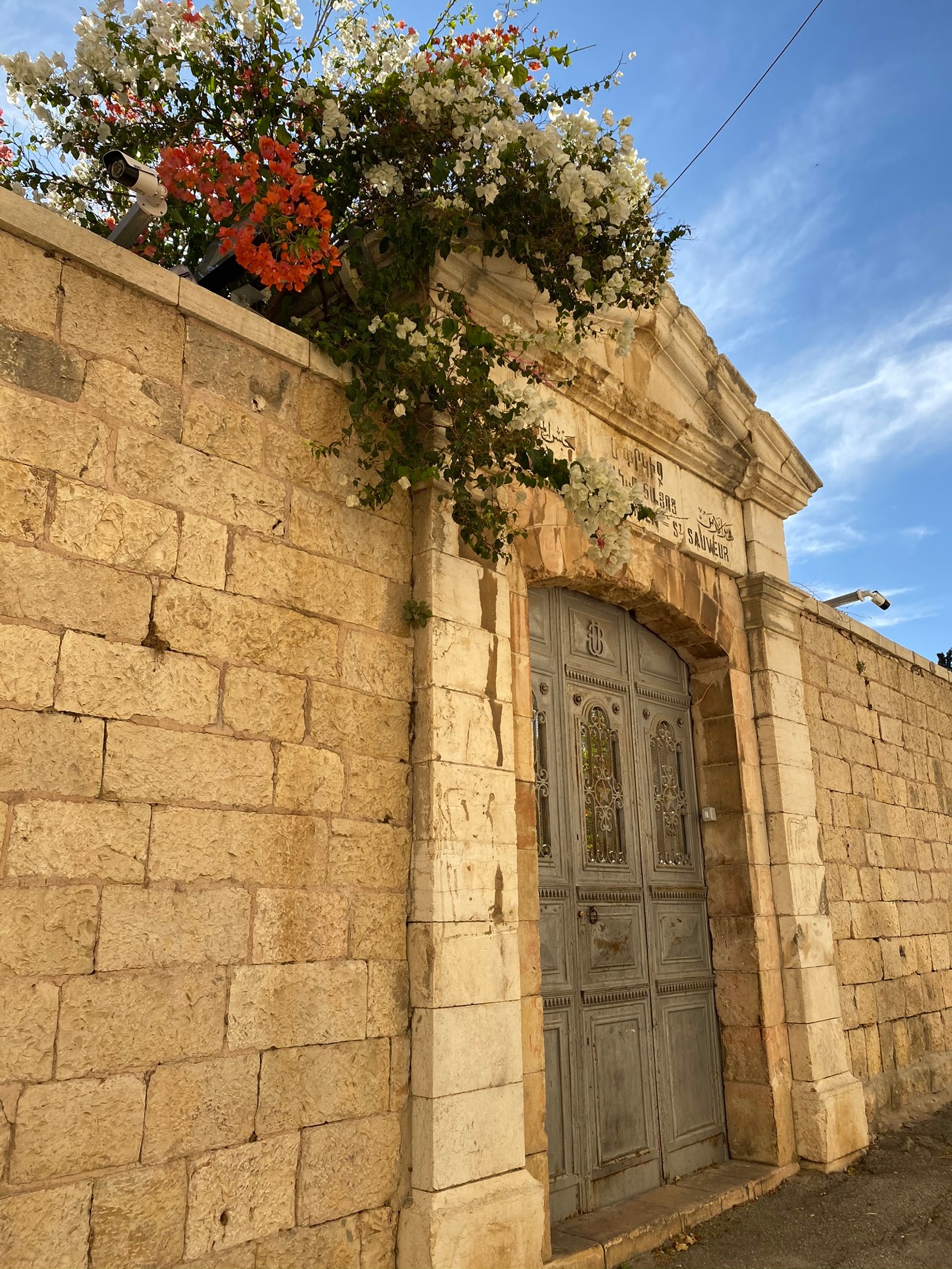 There is a stone wall with a door and a flower pot (wall, ancient history, historic site, stone wall, door)