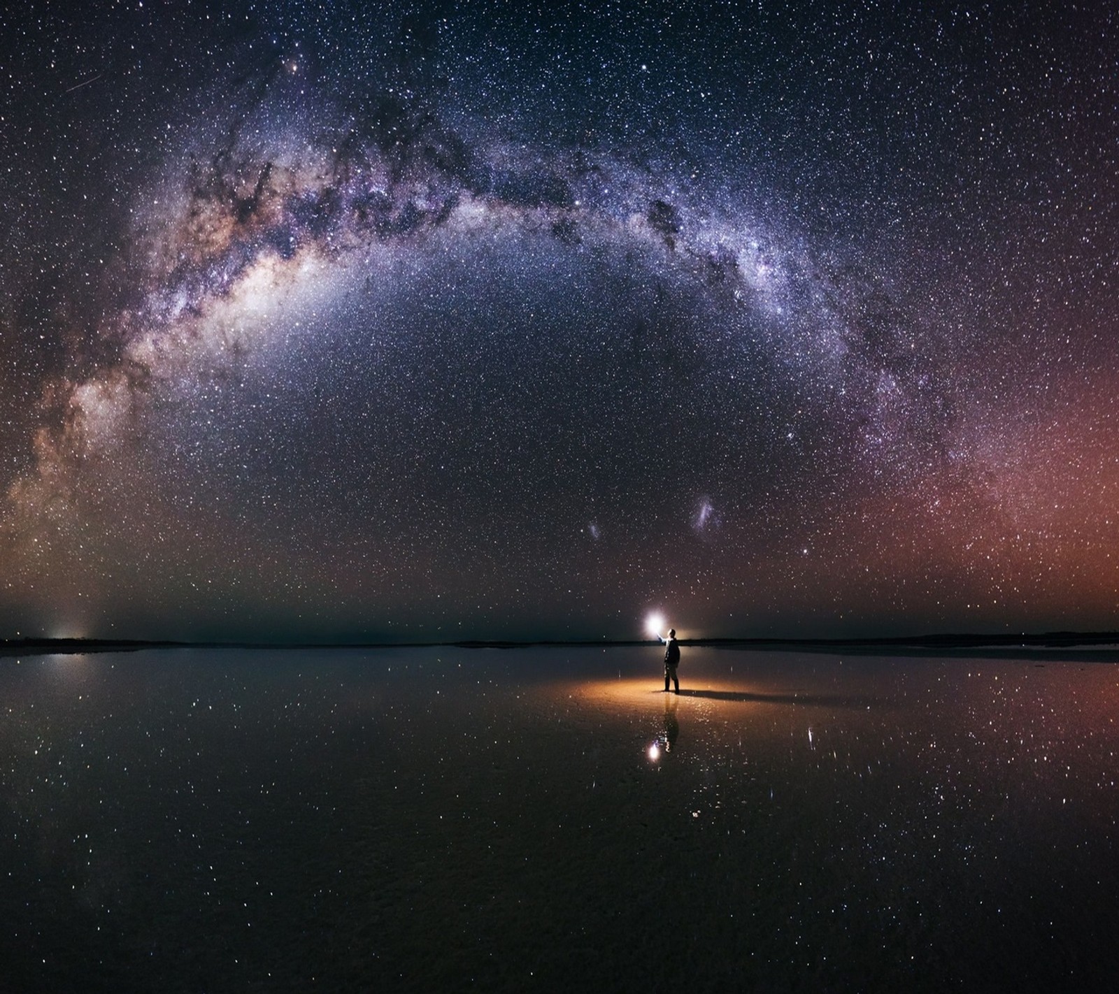 Uma pessoa em pé na praia sob uma grande galáxia (abej, beograd, via láctea)