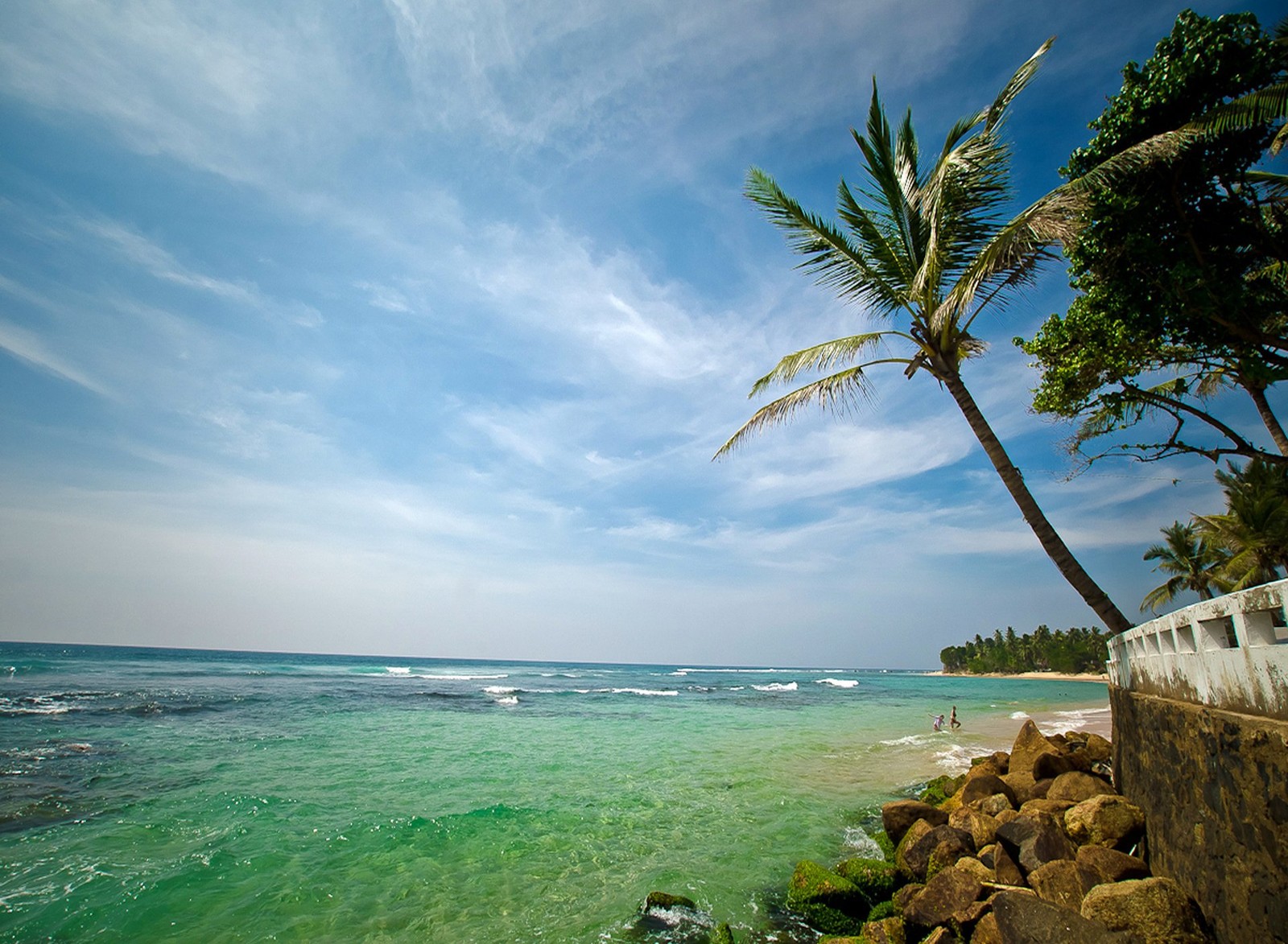 There is a man standing on a rock wall by the ocean (beach, hd, nature, wallpaper)